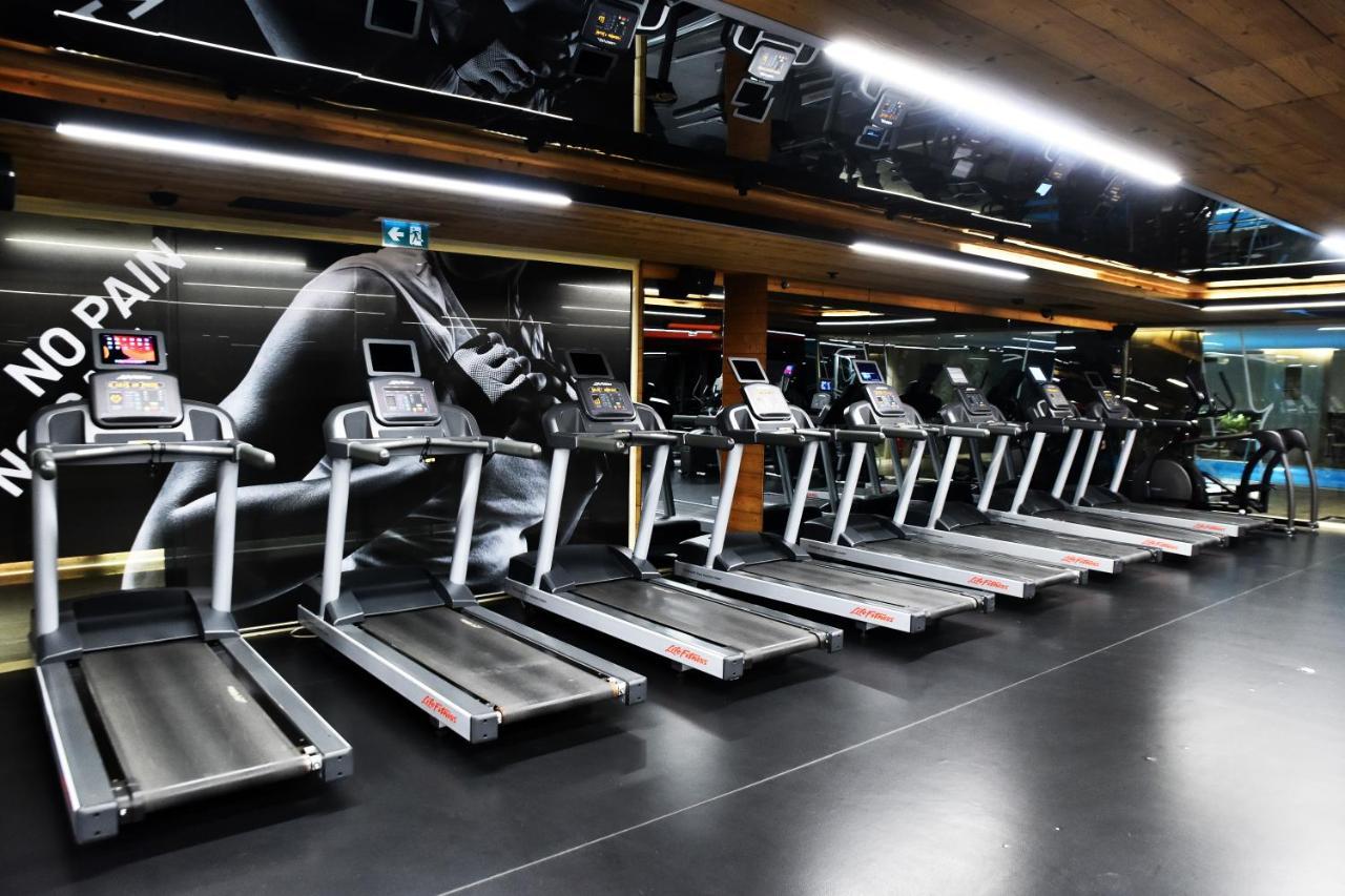 Dosso Dossi Hotels & Spa Downtown Istanbul Ngoại thất bức ảnh The photo shows a row of treadmills in a gym setting. The treadmills are modern and aligned next to each other on a sleek black floor. The background features a large image of a runner's foot, with motivational phrases that suggest themes of fitness 
