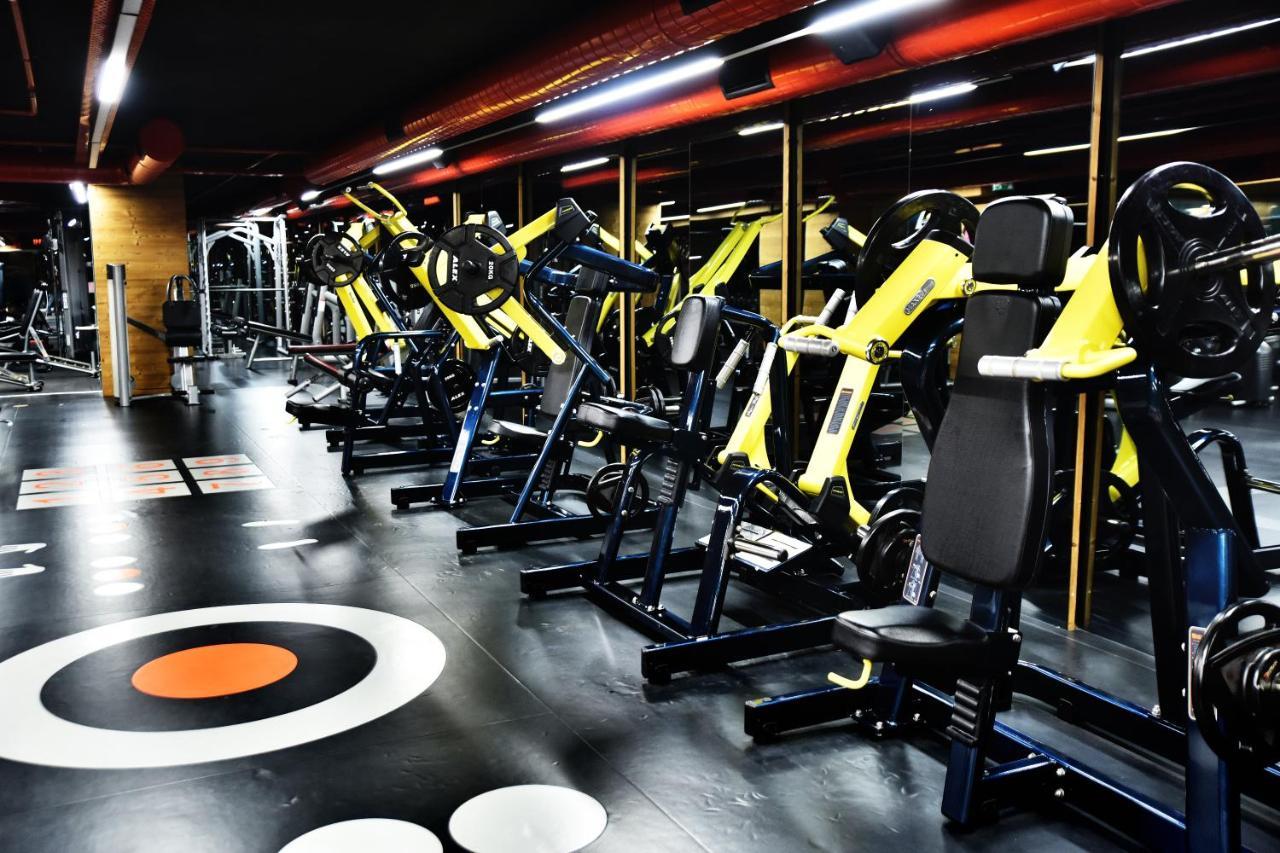 Dosso Dossi Hotels & Spa Downtown Istanbul Ngoại thất bức ảnh The photo shows a modern gym interior featuring various exercise machines. There are several yellow and black weight training machines aligned in rows, with a focus on strength training equipment. The flooring is dark with circular patterns, includin
