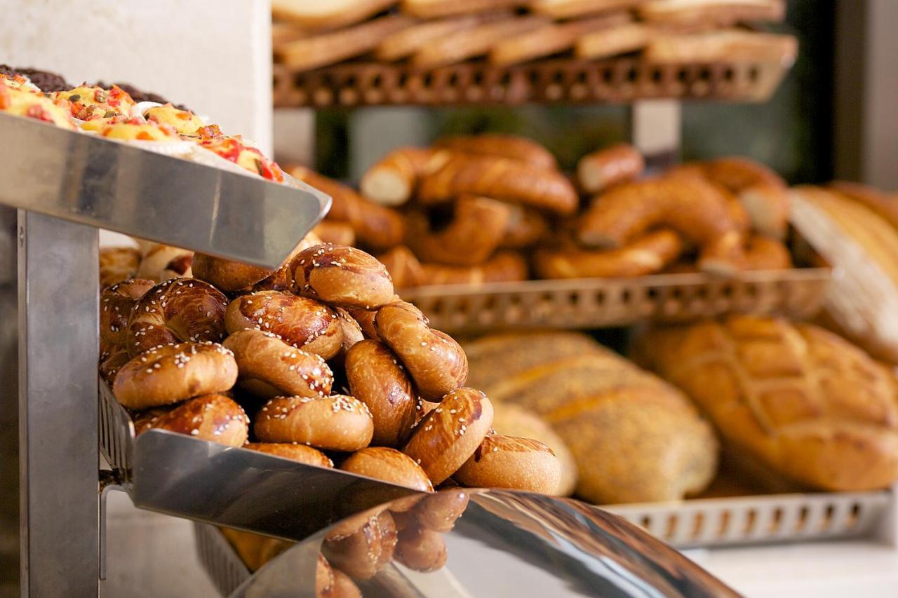 Dosso Dossi Hotels & Spa Downtown Istanbul Ngoại thất bức ảnh The photo shows a display of various types of baked goods. In the foreground, there are small, round bread rolls topped with sesame seeds. Behind them, multiple trays are stacked with an assortment of different breads, including twisted rolls and loa