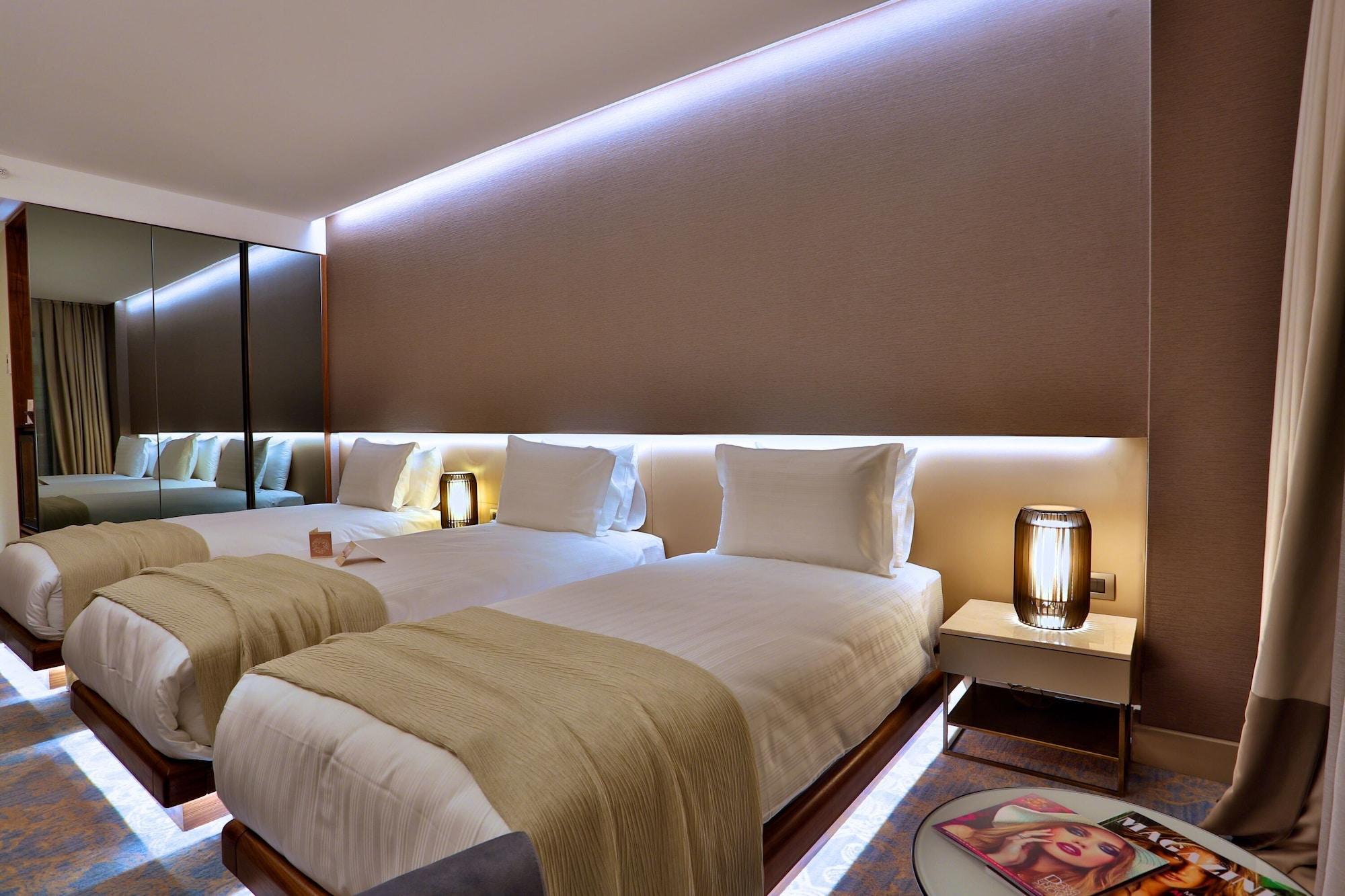 Dosso Dossi Hotels & Spa Downtown Istanbul Ngoại thất bức ảnh The photo shows a modern hotel room with two neatly made beds. Each bed is dressed with white linens and has a light-colored throw blanket. There are stylish bedside lamps on either side of the beds, as well as small nightstands. The wall behind the 
