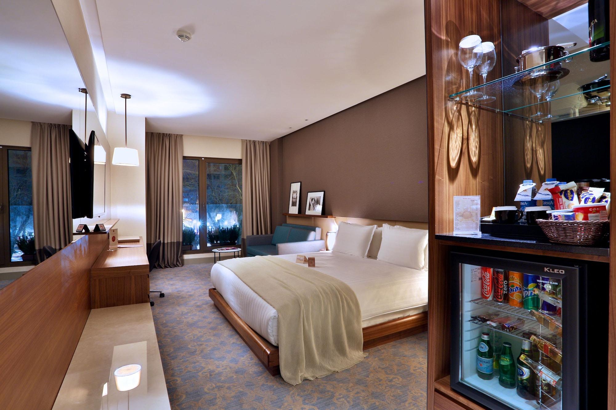 Dosso Dossi Hotels & Spa Downtown Istanbul Ngoại thất bức ảnh The photo shows a well-decorated hotel room featuring a large bed with white linens, a bedside table, and modern furnishings. There are two windows with curtains that allow natural light to enter the space, and the walls are painted in warm, neutral 