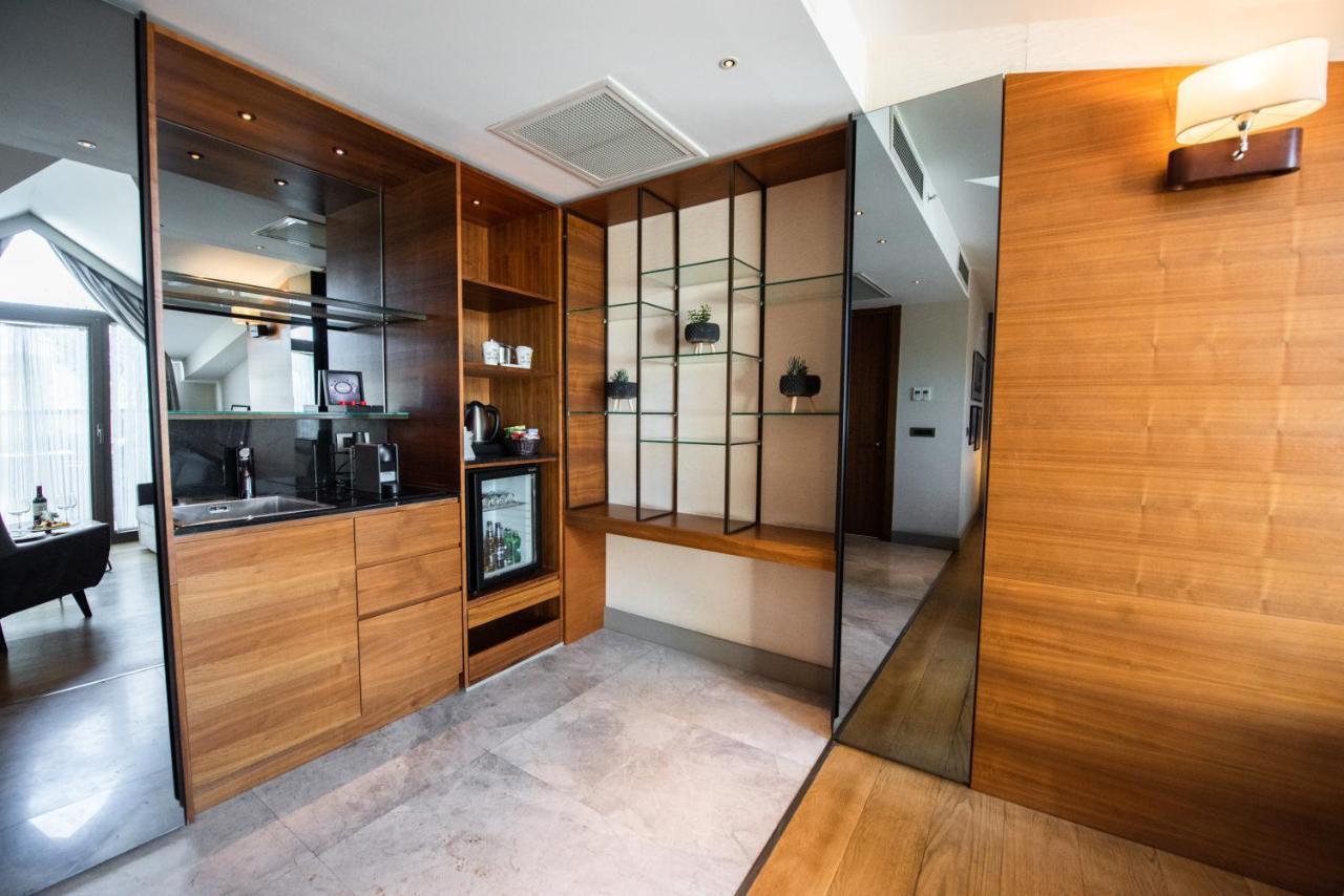 Dosso Dossi Hotels & Spa Downtown Istanbul Ngoại thất bức ảnh The photo shows a modern interior space that features a blend of wood and glass elements. On the left side, there is a kitchenette area with wooden cabinetry and a small refrigerator, while the right side showcases a glass display unit with shelves f