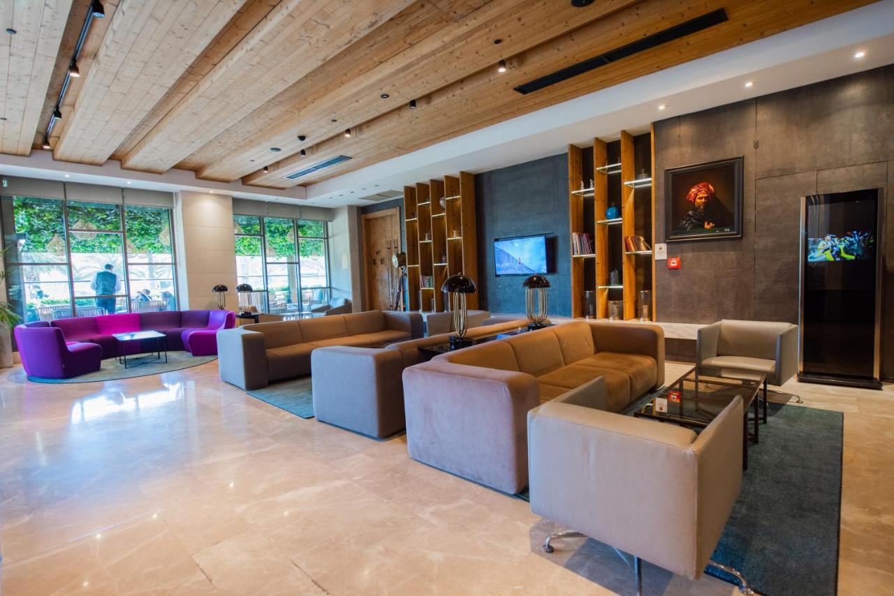 Dosso Dossi Hotels & Spa Downtown Istanbul Ngoại thất bức ảnh The photo shows a modern and stylish lobby area, featuring a combination of seating options. The space includes two large sofas in neutral colors, arranged around small glass tables. There are also individual armchairs and a more vibrant purple sofa 