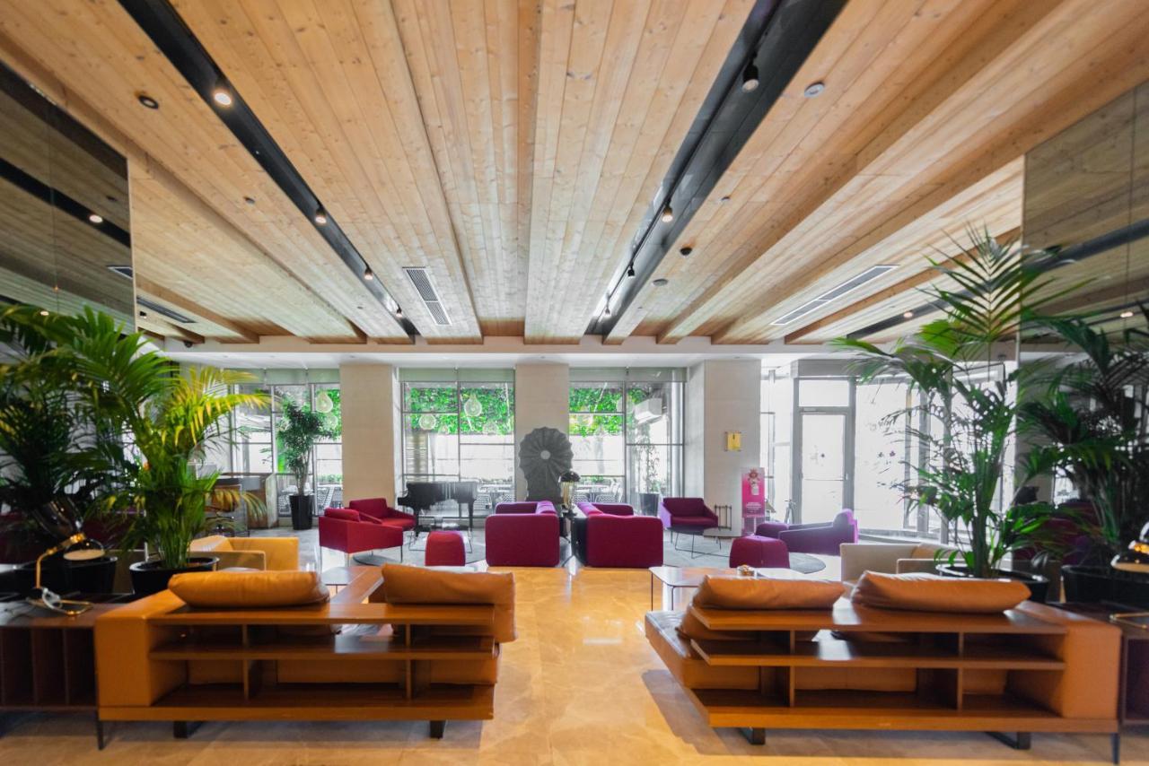 Dosso Dossi Hotels & Spa Downtown Istanbul Ngoại thất bức ảnh The photo shows a modern and spacious lobby area. There are wooden beams on the ceiling, giving the space a warm and inviting atmosphere. The flooring appears to be light-colored stone or tile. 

In the center of the room, there are several seating a