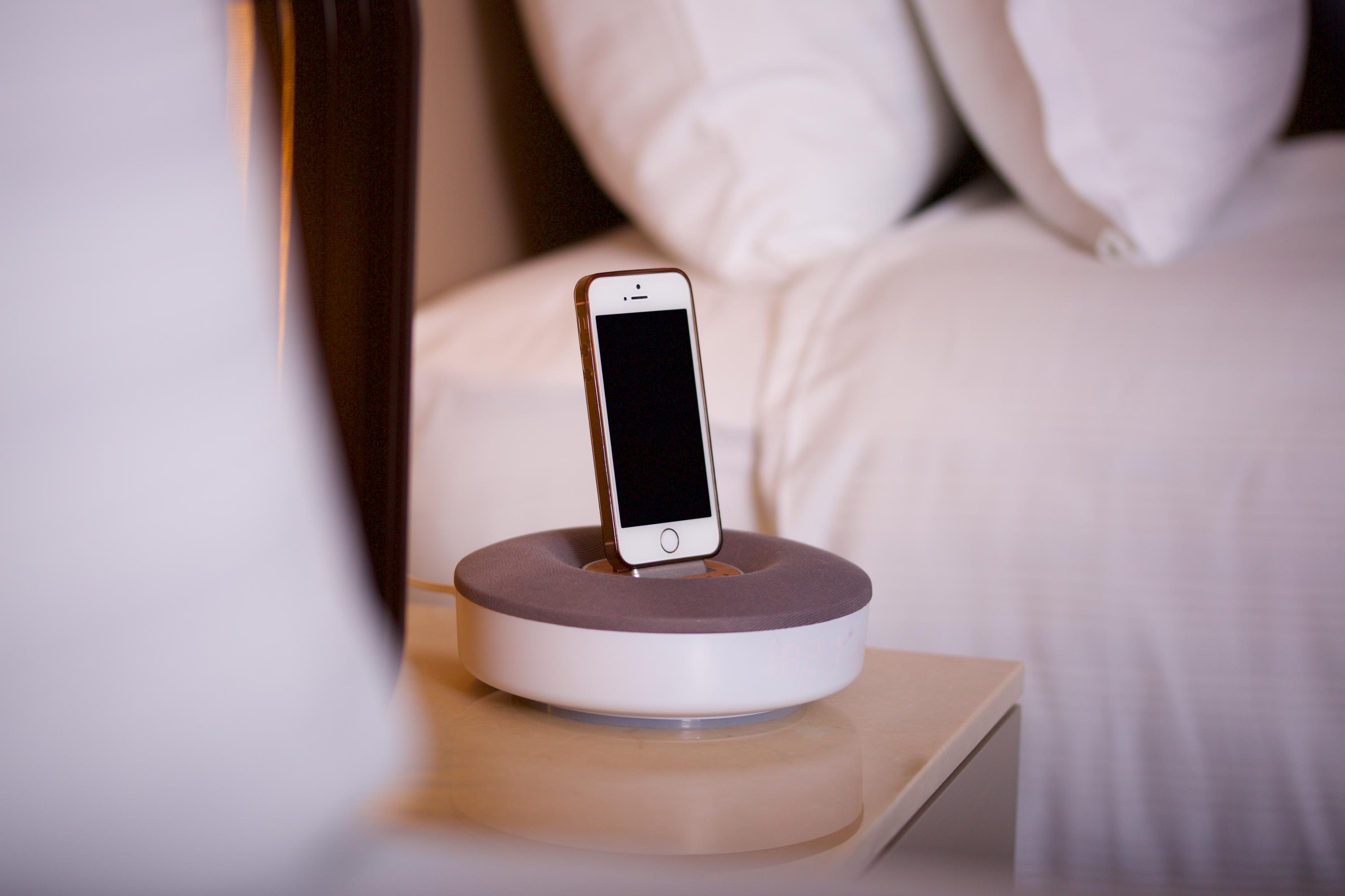Dosso Dossi Hotels & Spa Downtown Istanbul Ngoại thất bức ảnh The photo shows a smartphone placed on a charging dock. The dock has a circular base with a gray top and a white bottom. The smartphone is upright in the dock, facing forward, and has a blank screen. There are neatly arranged pillows visible in the b