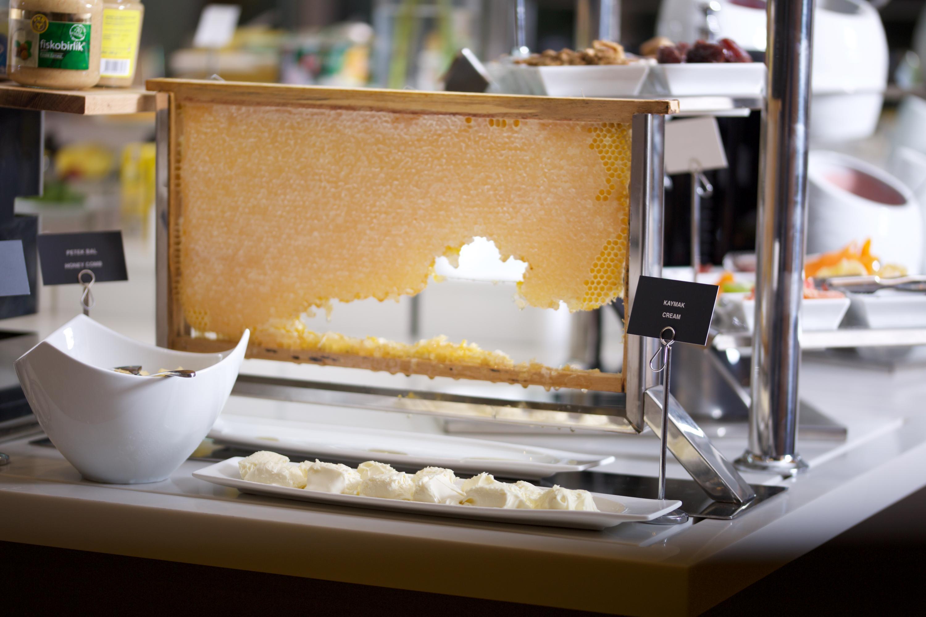 Dosso Dossi Hotels & Spa Downtown Istanbul Ngoại thất bức ảnh The photo shows a buffet setup featuring a large piece of honeycomb displayed in a frame, from which honey can be extracted. Below the honeycomb, there is a white dish containing small portions of what appears to be a creamy substance, likely a dairy