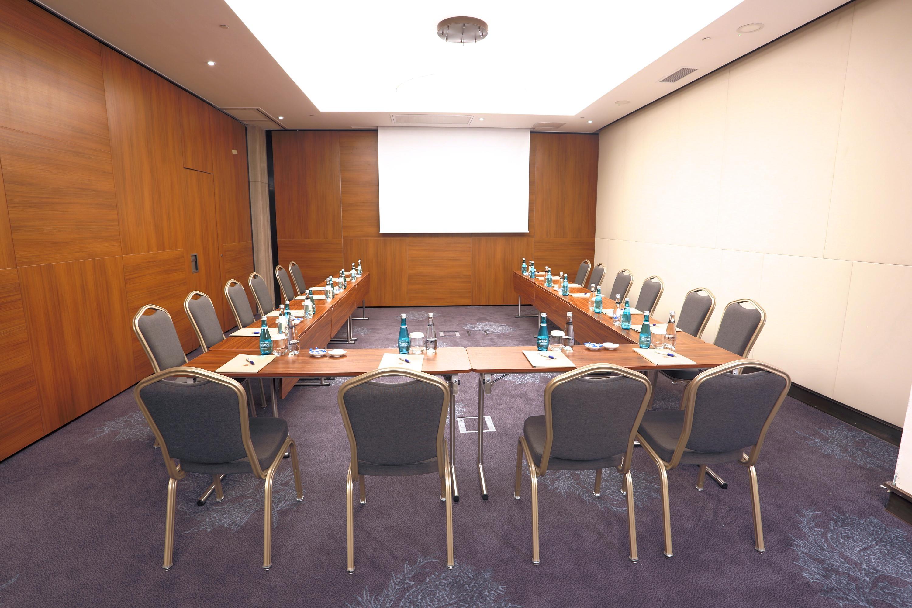 Dosso Dossi Hotels & Spa Downtown Istanbul Ngoại thất bức ảnh The photo shows a conference room setup. There are several rectangular tables arranged in a U-shape, surrounded by chairs. Each table has a water bottle and a notepad placed on it, suggesting it's intended for a meeting or presentation. The walls are