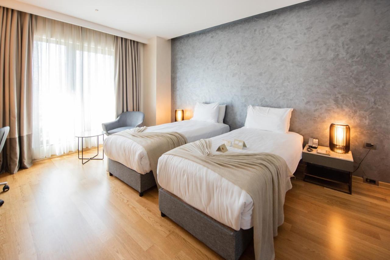Dosso Dossi Hotels & Spa Downtown Istanbul Ngoại thất bức ảnh The photo shows a modern hotel room featuring two single beds with white linens and soft gray throw blankets. The room has a stylish design, with wooden flooring and a large window dressed with light curtains that allow natural light to enter. There'