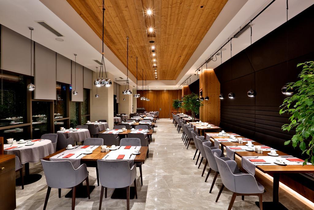 Dosso Dossi Hotels & Spa Downtown Istanbul Ngoại thất bức ảnh The photo depicts a modern restaurant interior. The space features a combination of wooden and polished surfaces, with a prominent wooden ceiling. 

Tables are set with white tablecloths and neatly arranged dishware, indicating a refined dining exper